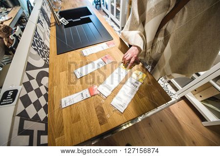 PARIS FRANCE - APR 12 2016: Woman coparing prices for diverse furniture sets and kitchen appliances