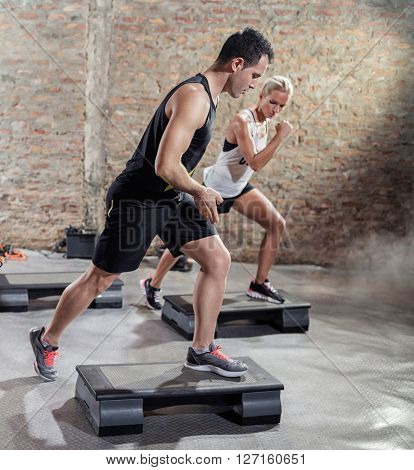 Sporty men train young woman  moves on stepper