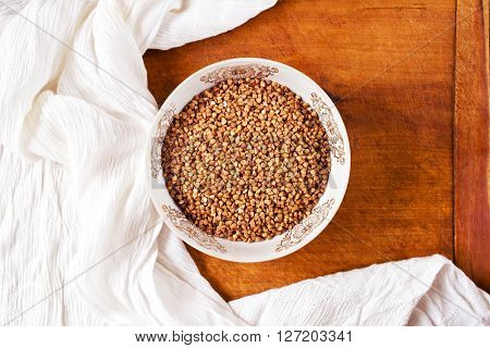 Dry buckwheat groats in a bowl on a wooden table