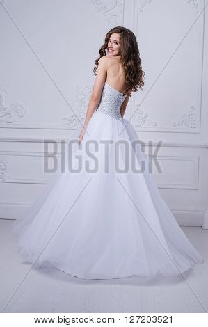 Gorgeous adorable brunette in wedding dress over rococo wall