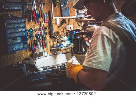 Gasoline Wood Cutter Chain Replacing in a Garage. Men Preparing Tools For Wood Cutter Chain Replacement.