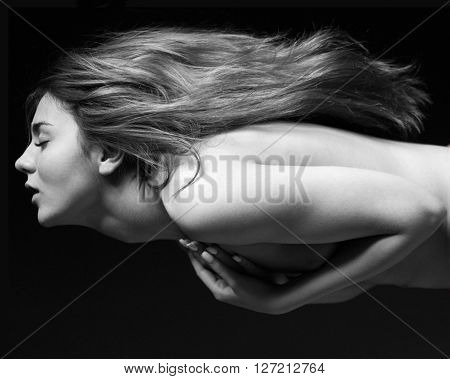 Naked female body and natural hair. Girl straightens hair his hands pressed to his body. Black and white portrait