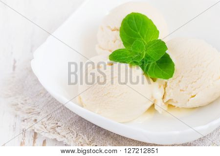 Ice cream in a white bowl with mint leaves.