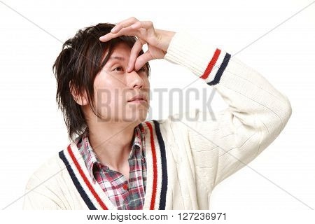 young Japanese man suffers from Asthenopia on white background