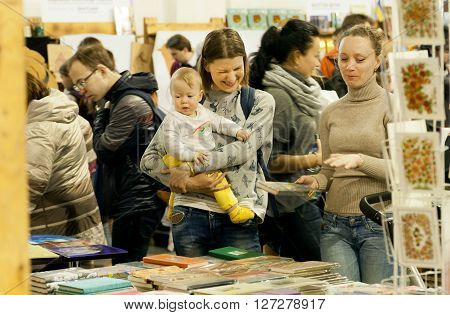 KYIV, UKRAINE - APR 21, 2016: Unidentified child and happy young mother making choice at the 6th Festival BOOK ARSENAL on April 21, 2016. Guests of fair were writers Lars Svendsen Vigdis Hjorth Etgar Keret