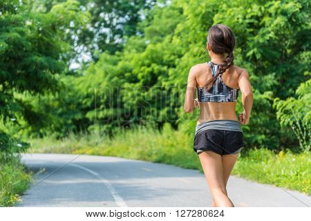 Active lifestyle girl runner running in summer city park living a healthy life. Jogger athlete woman from behind training cardio for weight loss of back thigh cellulite. Road to success to a fit body.