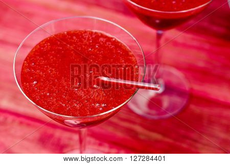 closeup of some cocktail glasses with fresh red smoothies on a red wooden surface