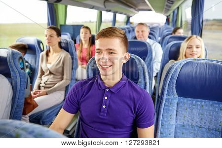 transport, tourism, road trip and people concept - happy young man sitting in travel bus or train