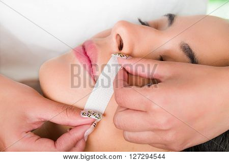 Closeup womans face receiving facial hair wax treatment, beauty and fashion concept.