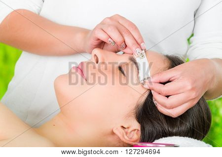 Closeup womans face receiving facial hair wax treatment, beauty and fashion concept.