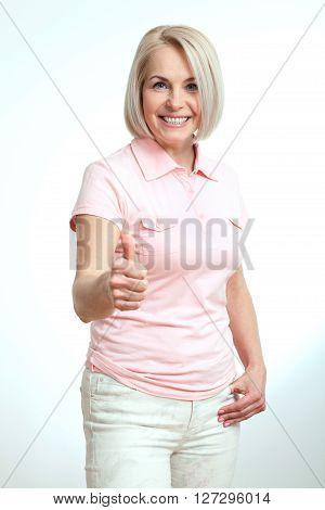 Smilling attractive middle aged woman showing thumbs up, okay. Isolated square