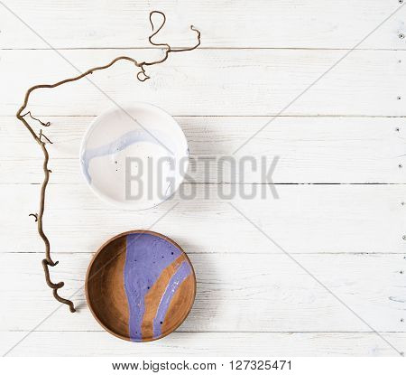 Top view empty creative handmade pottery plates with turquoise pattern on rustic wooden table.  Flat lay set of colorful clay dishes on white wooden background.