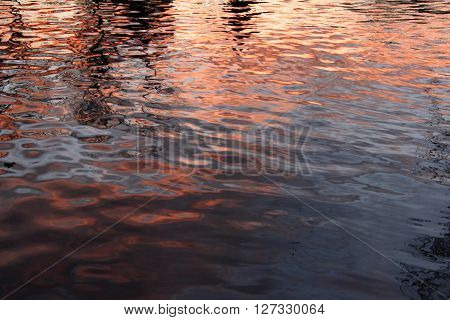 A sunset reflected on rippling lake water.