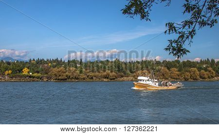 Small fishing seiner goes along the river to the sea for fishing