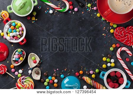 Colorful candies and coffee cup frame on stone background. Top view with copy space