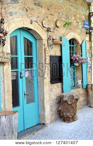 A facade in stones with a door and a window of color blue