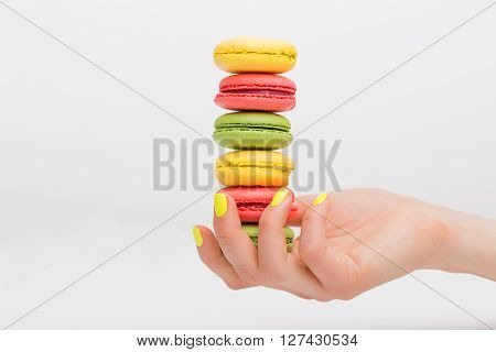 Person holding macaroon sweets in her palm
