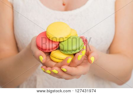 Woman holding many macaroons in both hands