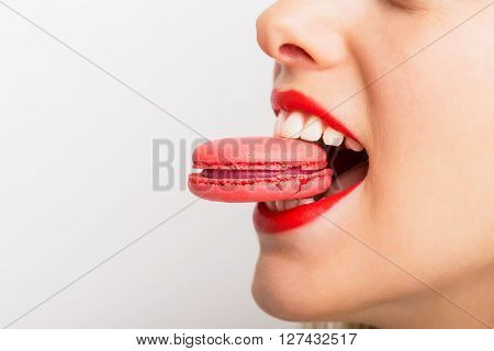 Woman taking a bite of pink macaroon