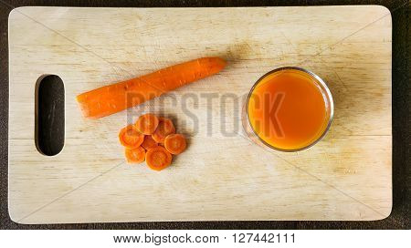 Fresh carrot juice on kitchen wooden plate