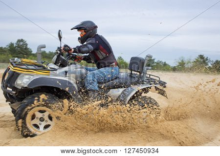 The race in difficult conditions on the sand on a quad bike.