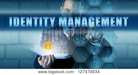 Manager pushing IDENTITY MANAGEMENT on a virtual interactive touch screen interface. Information technology security concept for managing the identification of individuals hardware and application.