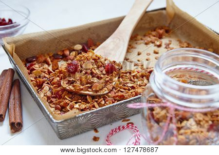 Homemade cinnamon granola, muesli with almond and cranberry in a baking pan.