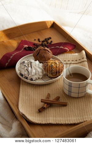 Sweet breakfast in bed served on tray with coffee and cupcakes