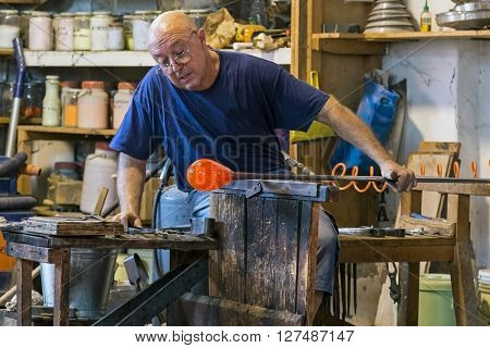 MURANO ITALY - AUGUST 5 2015: Glass worker in action in the Murano glass factory.