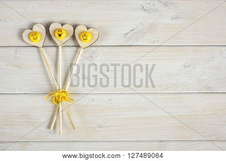 Icons of smiles on a wooden heart.
