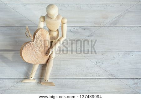 The dummy sits on the board and holding a wooden heart.