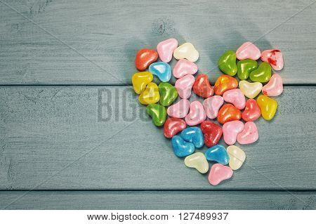 Heart and sweet colored candy on a wooden board.
