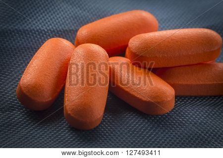 Macro close up orange pain killer pills on blue background