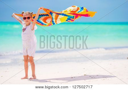 Little adorable girl with beach towel during tropical vacation