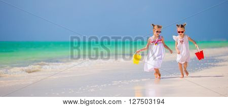 Adorable little girls have fun on white beach during vacation