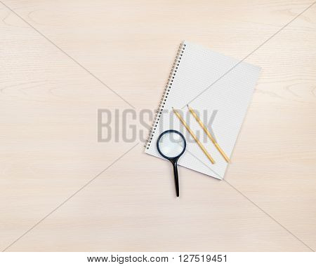 Magnifying Glass, Pencils And Notepad On Wooden Background.