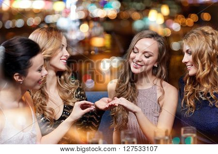 celebration, friends, bachelorette party and holidays concept - happy woman showing engagement ring to her friends with champagne glasses at night club