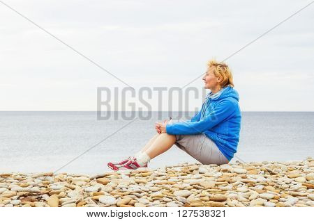 Woman sitting on the seaboard and looks into the distance