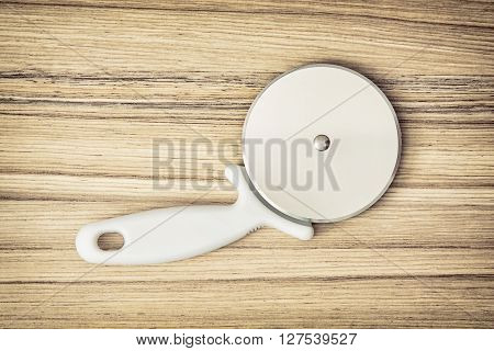 Pizza cutter on the wooden background. Kitchen equipment. Pizza slicer. Kitchen tool.