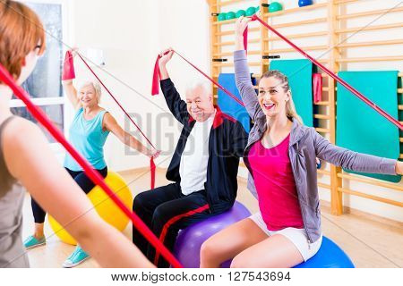 Senior people at fitness course in gym exercising with stretch band