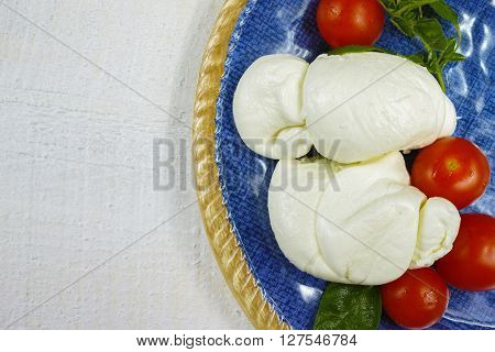 Traditional Italian mozzarella buffalo with tomatoes and basil on blue plate copy space