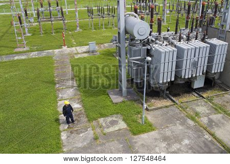 Worker in high voltage switchyard in electrical substation