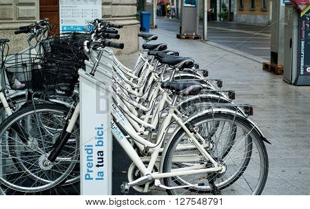 Lecco, Italy - September 2nd 2015: a row of white hire bicycles parked in the street in Lecco Lombardy Italy.