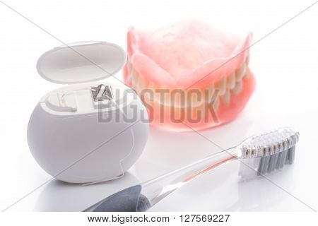 Teeth Model With Toothbrush And Dental Floss On White Background