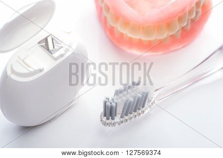 Teeth Model With Toothbrush And Dental Floss On White Background