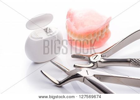 Teeth Model With Dental Floss And Forceps On White Background