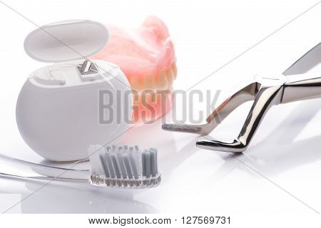 Teeth Model With Dental Floss, Toothbrush And Forceps On White Background