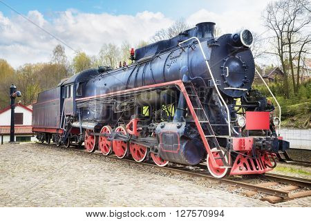 Old steam locomotive on rusty old rails and railway water tap