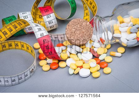 A Bottle Of Diet Pills With Measuring Tape