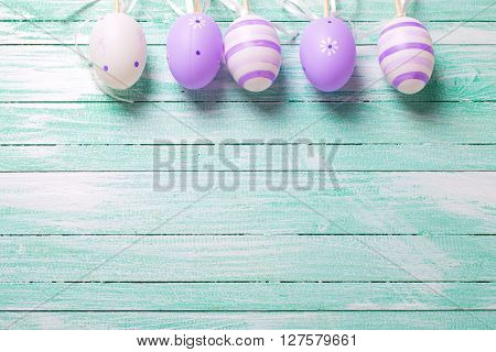 Easteror spring background. Decorative violet eggs on turquoise wooden background. Selective focus. Place for text.